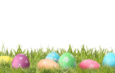 Beyaz arka plana karşı yeşil çimlerde paskalya yumurtaları