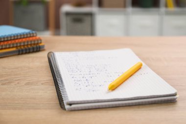 Ev ödevi. Matematik alıştırmalı defter ve tahta masa üzerindeki kalem, yakın plan. Metin için boşluk