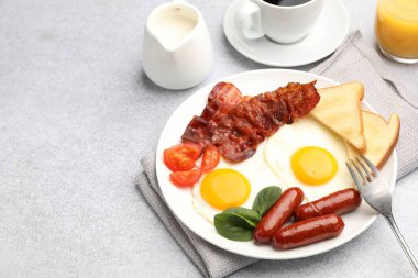 Açık gri masada servis edilen kızarmış yumurta, sosis ve pastırma ile nefis bir kahvaltı. Metin için boşluk
