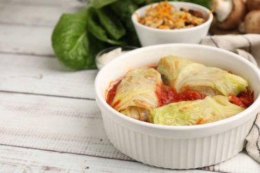 Doldurulmuş lahanalar hafif ahşap masada kasede yuvarlanıyor, yakın plan. Metin için boşluk