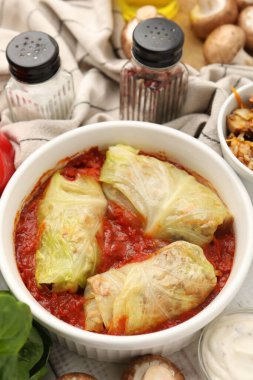 Lezzetli dolgulu lahana ruloları ve malzemeler masada, yakın plan.