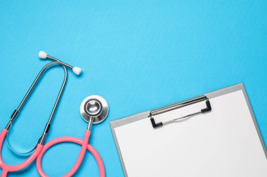 Açık mavi arka planda steteskop ve pano, üst manzara. Metin için boşluk