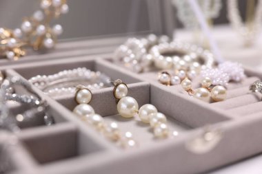 Beyaz masadaki kutuda farklı tarz mücevherler, yakın plan.