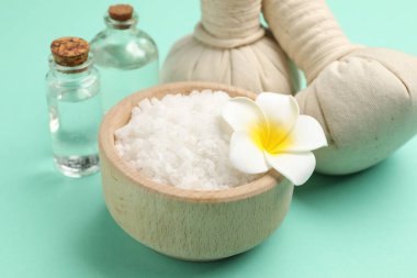 Kasede deniz tuzu, tesisat çiçeği, turkuaz arka planda gerekli yağlar ve bitkisel torbalar, yakın plan.