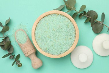 Kasede yeşil deniz tuzu, kepçe, masaj taşları ve turkuaz arka planda okaliptüs dalları.