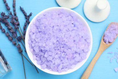 Mor deniz tuzu kasede, masaj taşları, lavanta çiçekleri açık mavi ahşap masada, düz yerde.