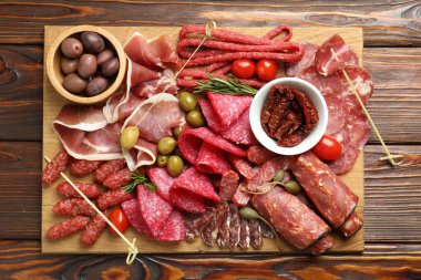 Şarküteri tahtası, farklı pişirilmiş et, sosis ve ahşap masa üzerinde zeytin, üst manzara.
