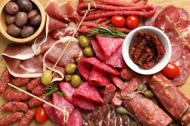 Şarküteri tahtasında farklı pişirilmiş et, sosis ve zeytin var.