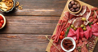 Şarküteri tahtası, farklı pişirilmiş et, sosis ve ahşap masa üzerinde zeytin, düz yatak. Metin için boşluk