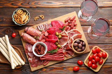 Farklı pişirilmiş et, sosis, domates, zeytin ve şarapla ahşap masa, düzlük.