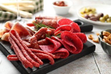 Şarküteri tahtası, beyaz fayanslı masa üzerinde farklı pişirilmiş et ve sosisler, yakın plan.