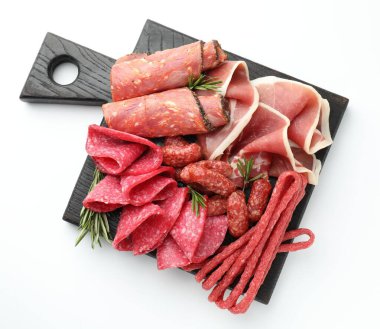 Farklı kesilmiş et, sosis ve beyaz arka planda biberiye içeren şarküteri tahtası.