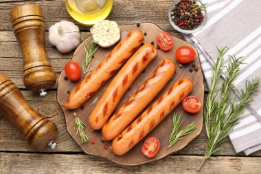 Izgara sosisler, domatesler ve baharatlar ahşap masada, düz yatıyordu.