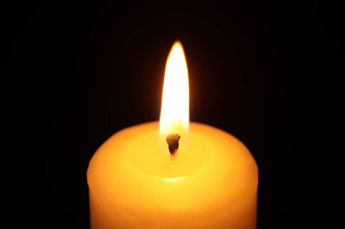 Siyah arkaplanda yanan bir mum, yakın plan.