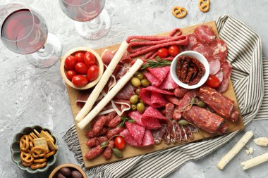 Şarküteri tahtası, farklı pişirilmiş et, sosis ve şarap gri masada, düz yatıyordu.