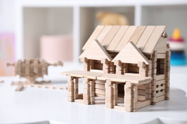 Beyaz masadaki tahta bloklardan yapılmış ev figürü. Kapalı, yakın plan.