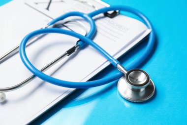 Açık mavi arkaplanda stetoskop ve pano, yakın plan