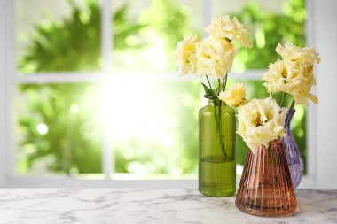 Pencerenin karşısındaki masada vazodaki Eustoma çiçekleri. Güzel kompozisyon