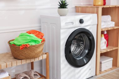 Çamaşır sepetinde çamaşır makinesinin yanında kirli çamaşırlar.