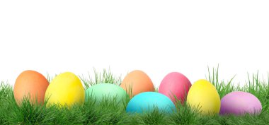 Beyaz arka plana karşı yeşil çimlerde paskalya yumurtaları