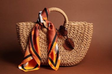 Şık mendil, güneş gözlüğü ve kahverengi arka planda çanta.