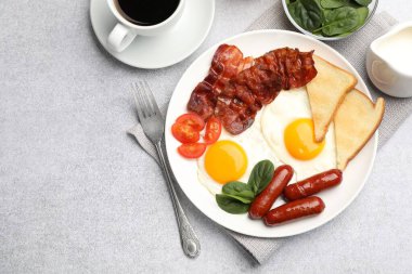 Açık gri masada servis edilen kızarmış yumurta, sosis ve domuz pastırması ile nefis bir kahvaltı. Metin için boşluk