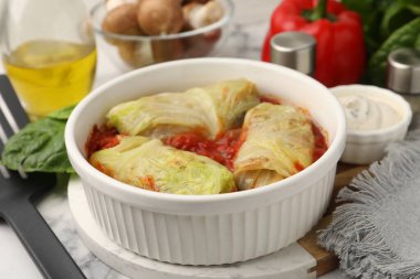 Lezzetli dolgulu lahana ruloları ve malzemeler masada, yakın plan.