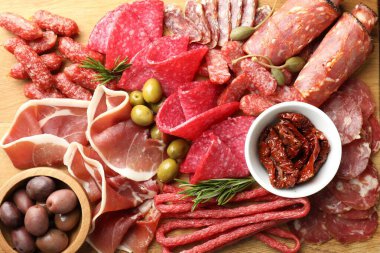 Şarküteri tahtasında farklı pişirilmiş et, sosis ve zeytin var.