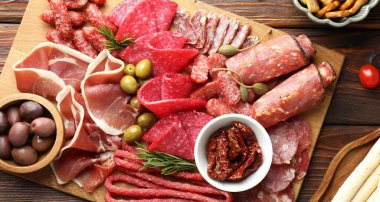 Şarküteri tahtası, farklı pişirilmiş et, sosis ve ahşap masa üzerinde zeytin, düz yatıyordu.