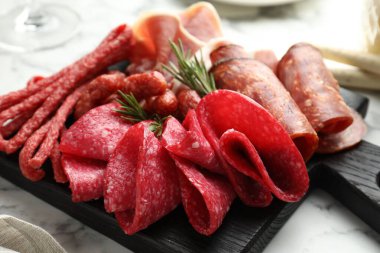 Şarküteri tahtası beyaz mermer masa üzerinde farklı pişirilmiş et ve sosisler, yakın plan.