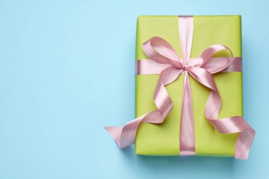 Açık mavi arka planda parlak hediye kutusu, üst manzara. Metin için boşluk