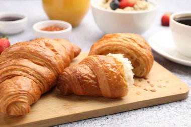 Nefis bir kahvaltı. Lezzetli kruvasanlar, yulaf ezmesi ve kahve açık gri masada, yakın plan.