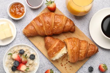 Nefis bir kahvaltı. Lezzetli kruvasanlar, reçeller, böğürtlenler, yulaf ezmesi ve içecekler açık gri masada, düz yatıyordu.