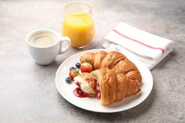 Nefis bir kahvaltı. Reçelli lezzetli kruvasanlar, açık gri masada böğürtlen ve içecekler, yakın plan.
