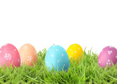 Beyaz arka plana karşı yeşil çimlerde paskalya yumurtaları