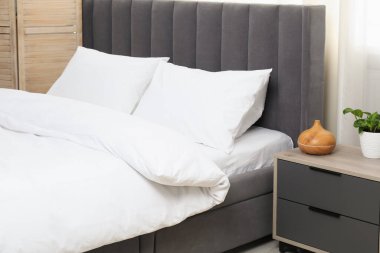 Yatak odasında temiz beyaz çarşafları olan rahat bir yatak.