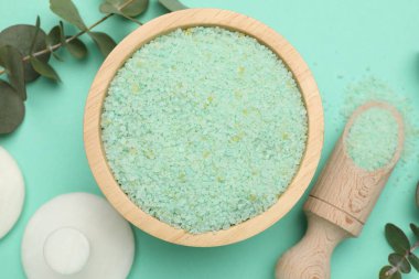 Kasede yeşil deniz tuzu, kepçe, masaj taşı ve turkuaz arka planda okaliptüs dalları.