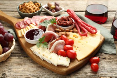 Tahta masa üzerinde farklı atıştırmalıklar ve şaraplar olan şarküteri tahtası, yakın plan.