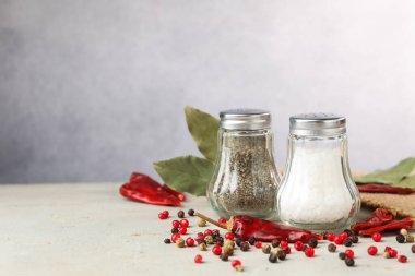 Açık gri masada baharatlı tuzluk ve biberlikler, yakın plan. Metin için boşluk