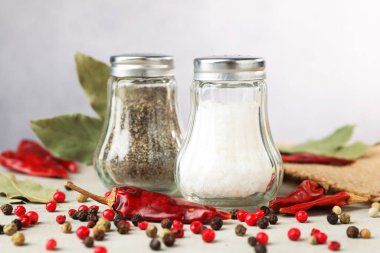 Açık gri masada baharatlı tuzluk ve biberlikler, yakın plan.