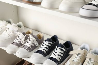 Raf ünitesinde farklı stil çocuk ayakkabıları var. Kapalı, yakın çekim.