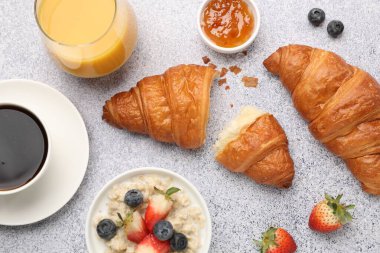 Nefis bir kahvaltı. Lezzetli kruvasanlar, reçeller, böğürtlenler, yulaf ezmesi ve içecekler açık gri masada, düz yatıyordu.