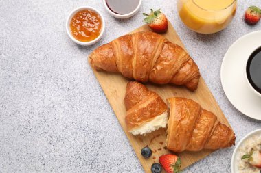 Nefis bir kahvaltı. Lezzetli kruvasanlar, reçel, böğürtlen, yulaf ezmesi ve açık gri masada içecekler. Metin için boşluk