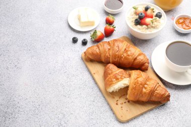 Nefis bir kahvaltı. Lezzetli kruvasanlar, reçel, böğürtlen, yulaf ezmesi ve açık gri masada kahve. Metin için boşluk