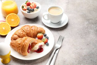 Nefis bir kahvaltı. Reçelli lezzetli kruvasanlar, böğürtlenler, içecekler ve açık gri masada yulaf ezmesi, yakın plan. Metin için boşluk