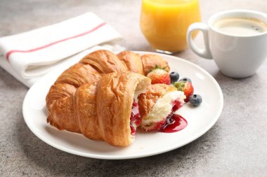 Nefis bir kahvaltı. Reçelli lezzetli kruvasanlar, açık gri masada böğürtlen ve içecekler, yakın plan.