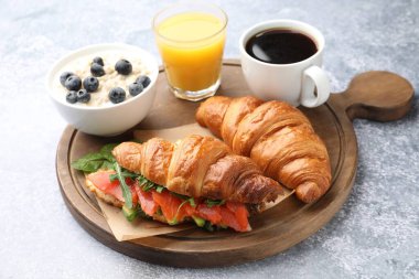 Sağlıklı kahvaltı. Açık gri masada somon, meyve suyu, kahve ve yulaf ezmeli lezzetli kruvasan. Yakın plan.