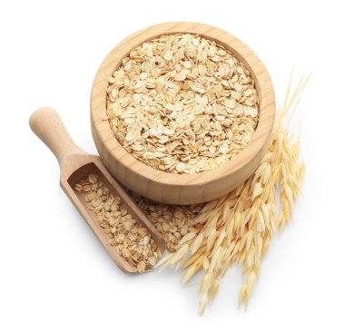 Tahta kasede yulaf ezmesi, kepçeler ve çiçeklerin beyaza izole edilmiş hali.