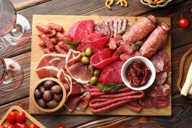 Farklı pişirilmiş et, sosis, domates, zeytin ve şarapla ahşap masa, düzlük.