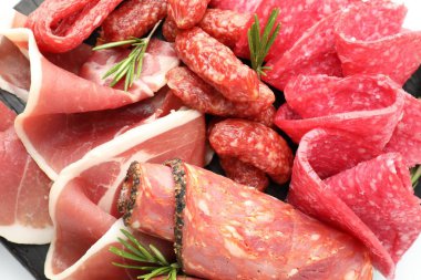 Farklı kesilmiş et, sosis ve biberiye içeren şarküteri tahtası.